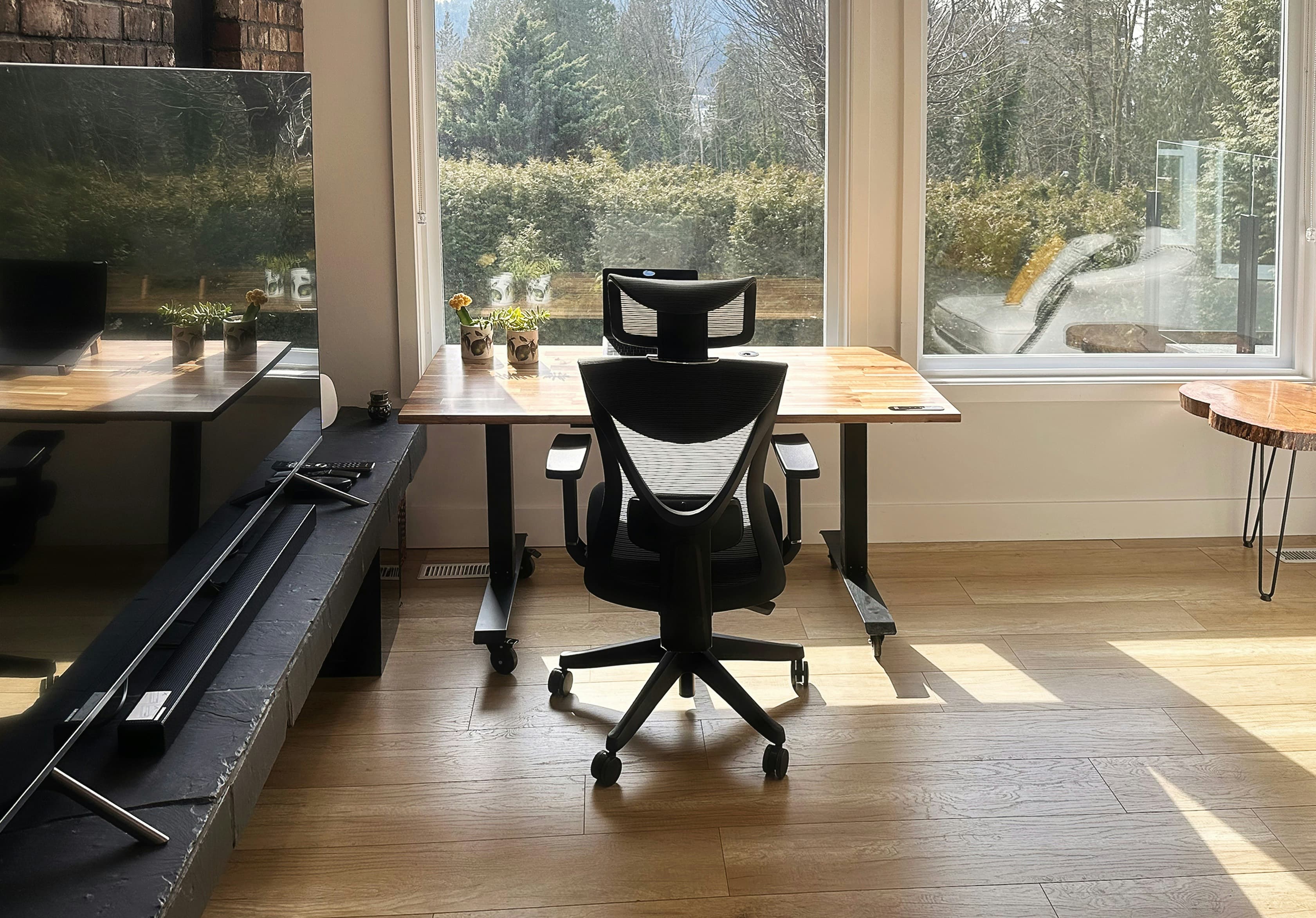 Ergonomic office chair facing a window, placed in front of a wooden home-office desk