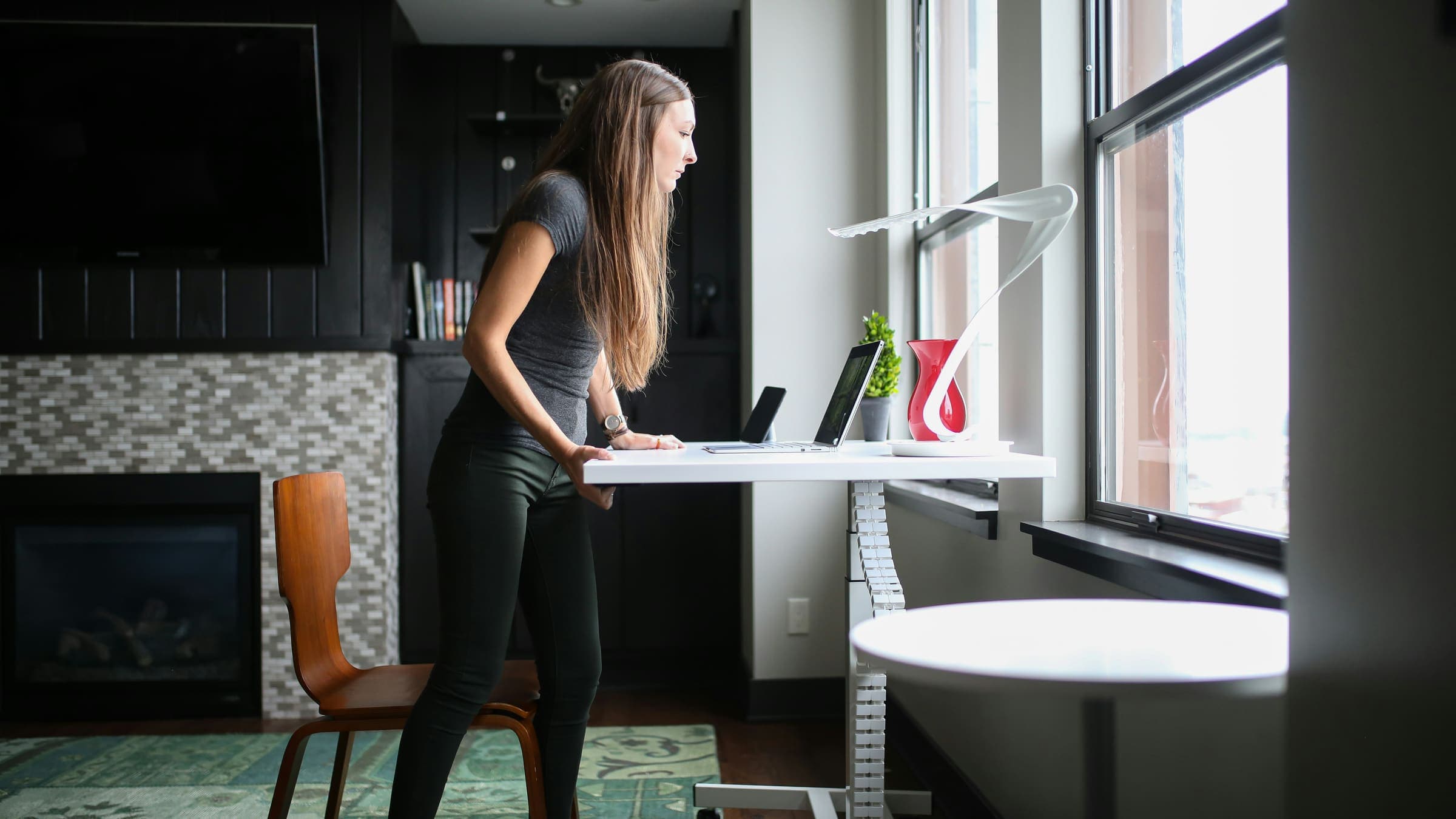 Person standing at an adjustable desk near a window