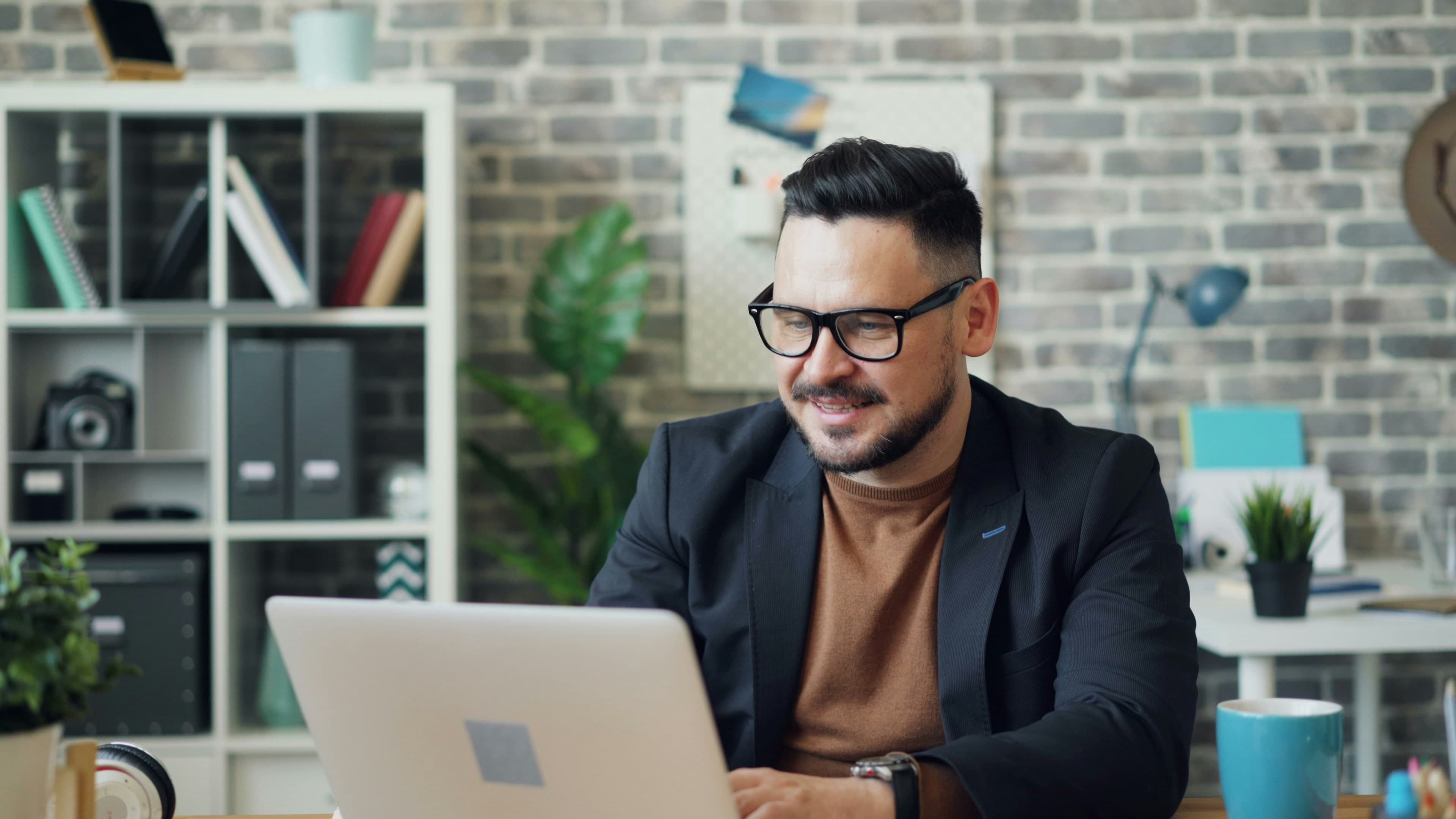 Remote worker taking an active break with arms stretched behind a desk and laptop