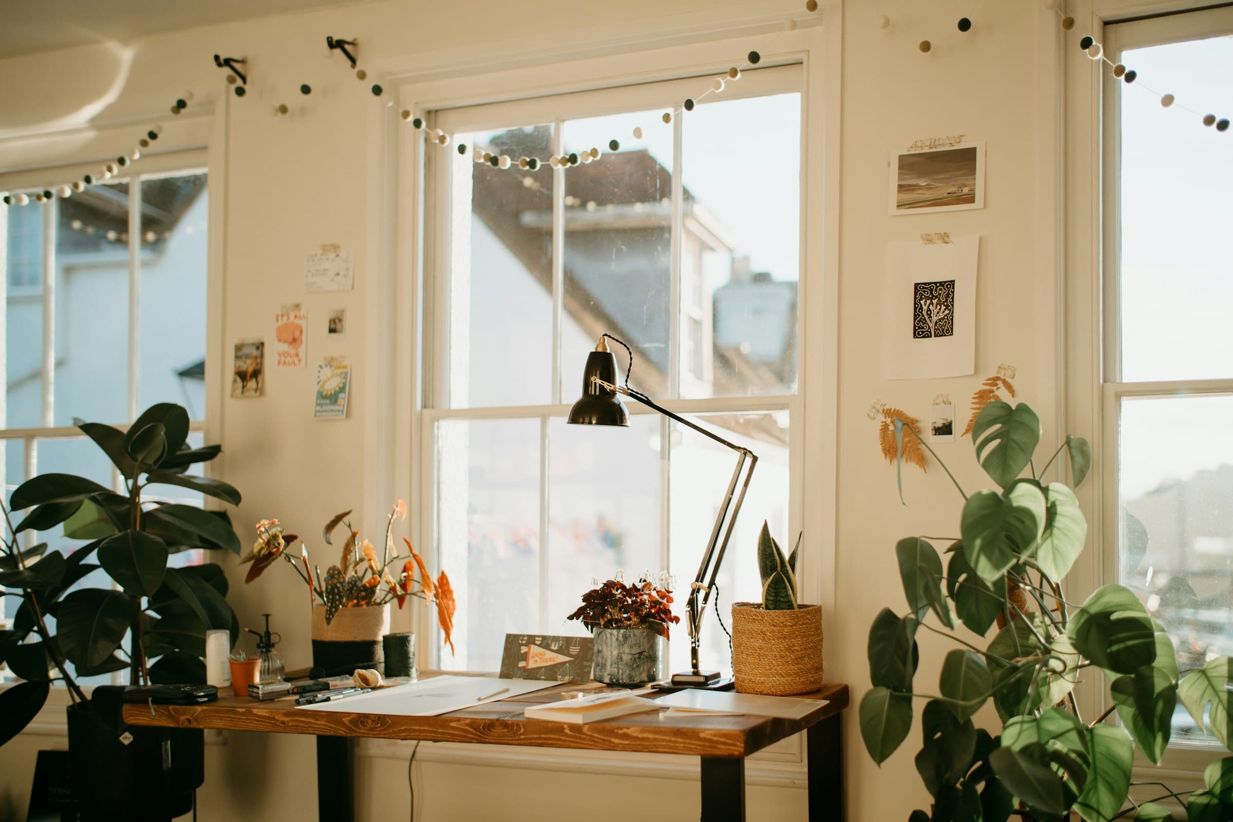 Bureau de télétravail calme près d'une fenêtre, avec lampe, plantes, carnet et lumière naturelle