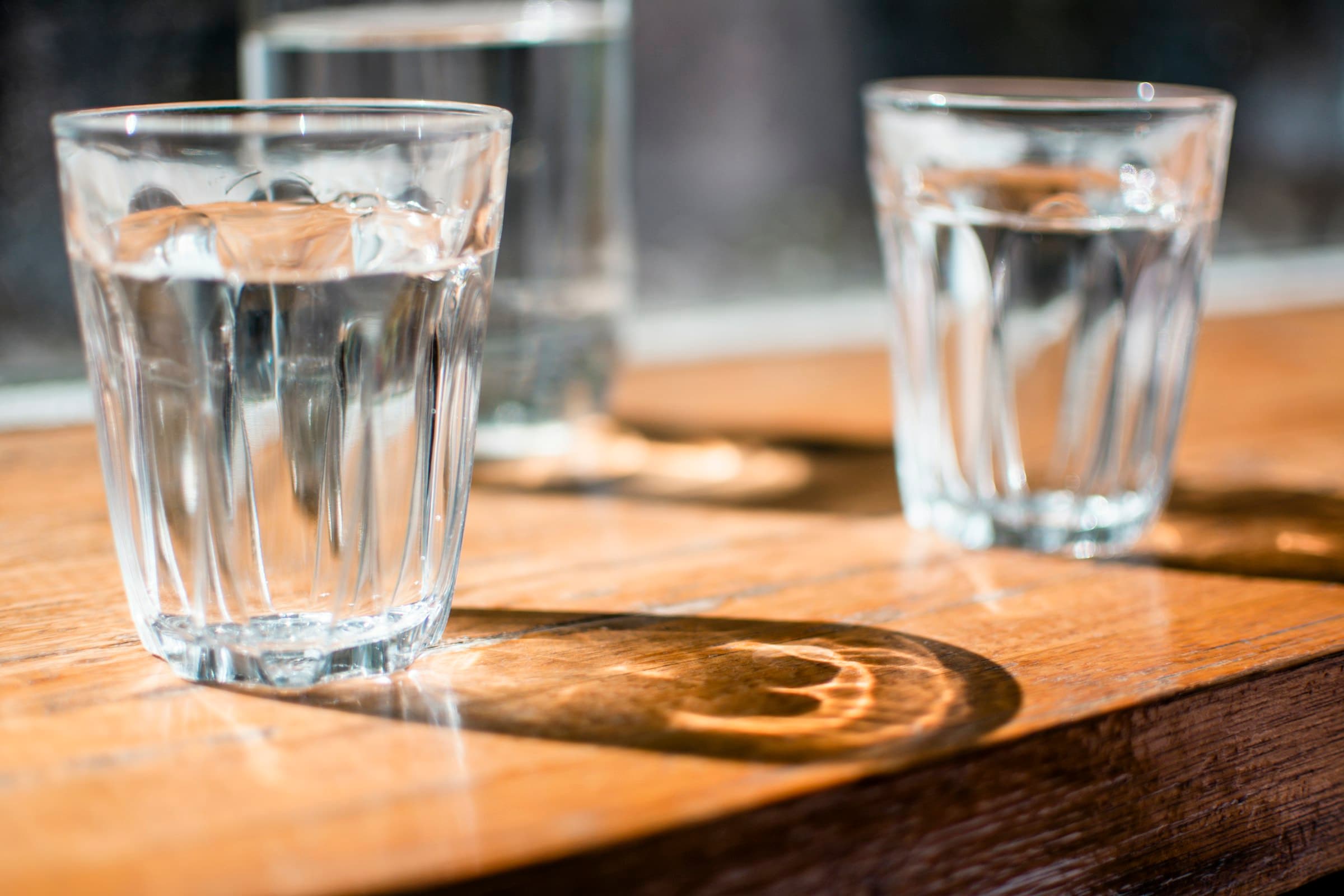 Verres d'eau sur une table en bois dans une lumière naturelle calme